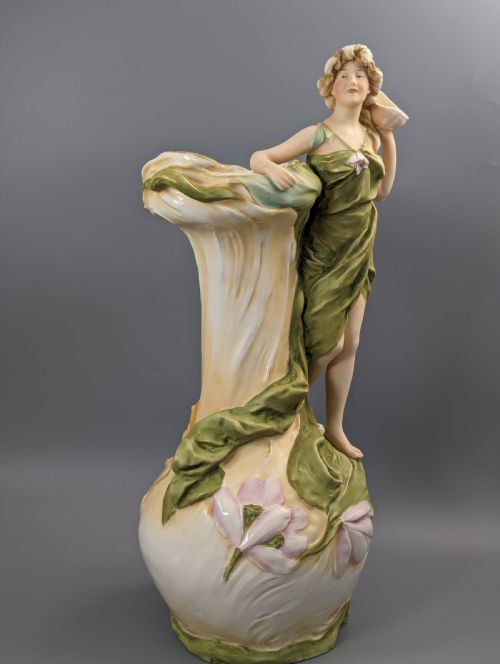 fig 6. An Art Nouveau Royal Dux porcelain vase depicting a draped water nymph holding a seashell against flowing foliage in cream, olive green, and soft pink shades.