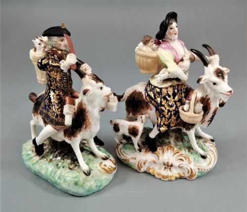 fig 4. A pair of painted porcelain figurines depicting a man and woman in 18th-century attire riding goats with cobalt blue gilded jackets on rococo scroll bases.