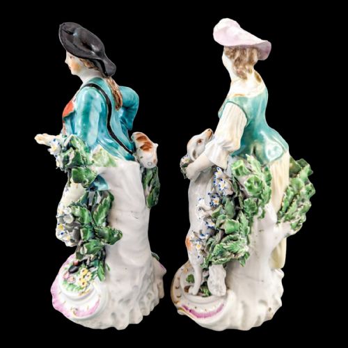 fig 2. A pair of eighteenth-century Derby soft-paste porcelain figurines depicting a shepherd and shepherdess adorned in floral-patterned garments with garlands on scroll bases.