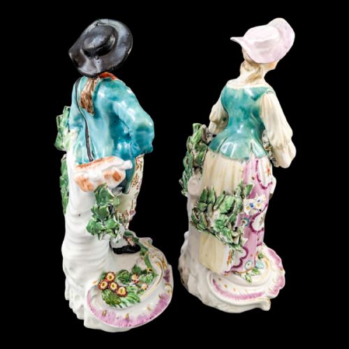 fig 4. A pair of eighteenth-century Derby soft-paste porcelain figurines depicting a shepherd and shepherdess adorned in floral-patterned garments with garlands on scroll bases.
