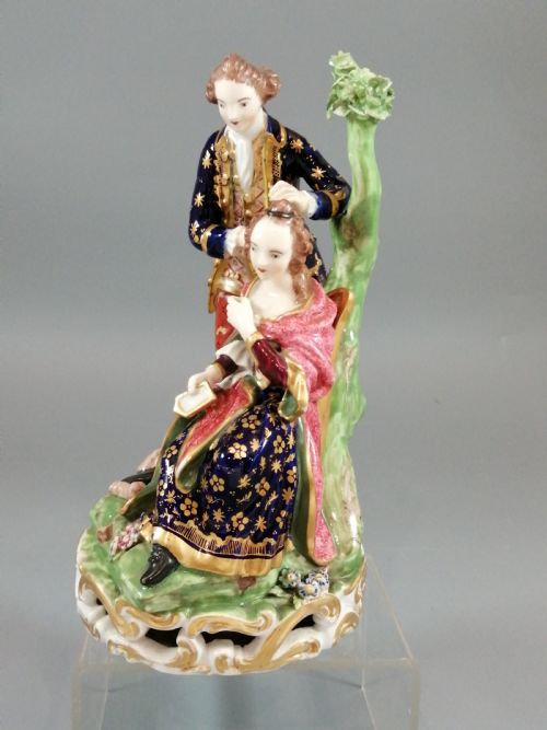 fig 1. An early nineteenth-century painted porcelain figurine depicting a male court hairdresser styling a seated ladys hair on a rococo scroll base.