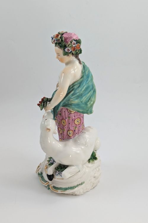 fig 2. An 18th-century Derby porcelain allegorical figure depicting Asia wearing a floral crown and patterned pink drapery alongside a camel on a scrollwork base.