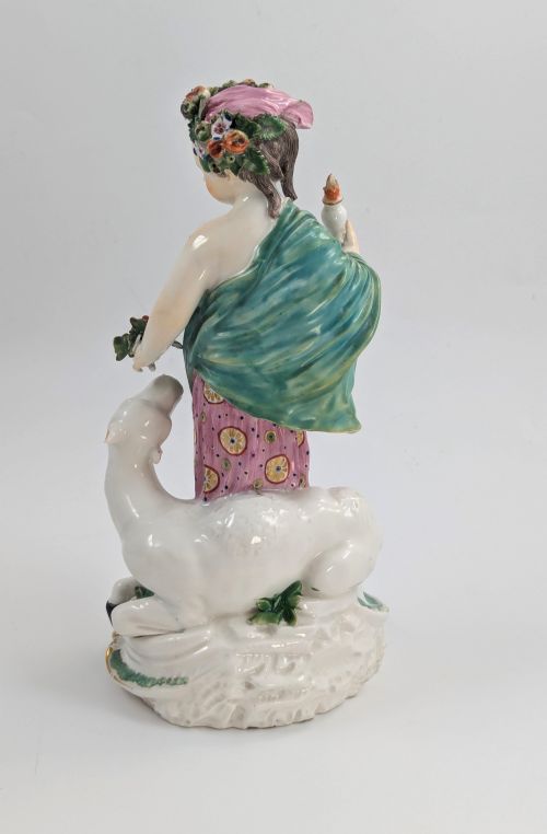 fig 3. An 18th-century Derby porcelain allegorical figure depicting Asia wearing a floral crown and patterned pink drapery alongside a camel on a scrollwork base.