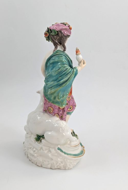 fig 4. An 18th-century Derby porcelain allegorical figure depicting Asia wearing a floral crown and patterned pink drapery alongside a camel on a scrollwork base.