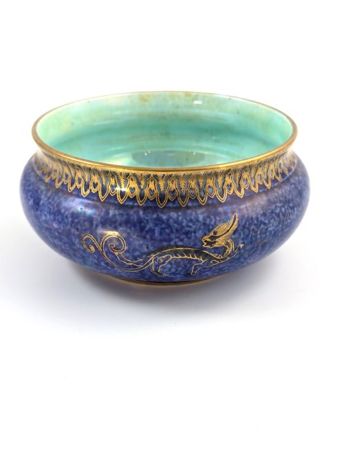 fig 2. A rounded ceramic bowl featuring a mottled blue exterior decorated with a gilded dragon motif, a gilt patterned rim, and a pale iridescent green interior glaze.