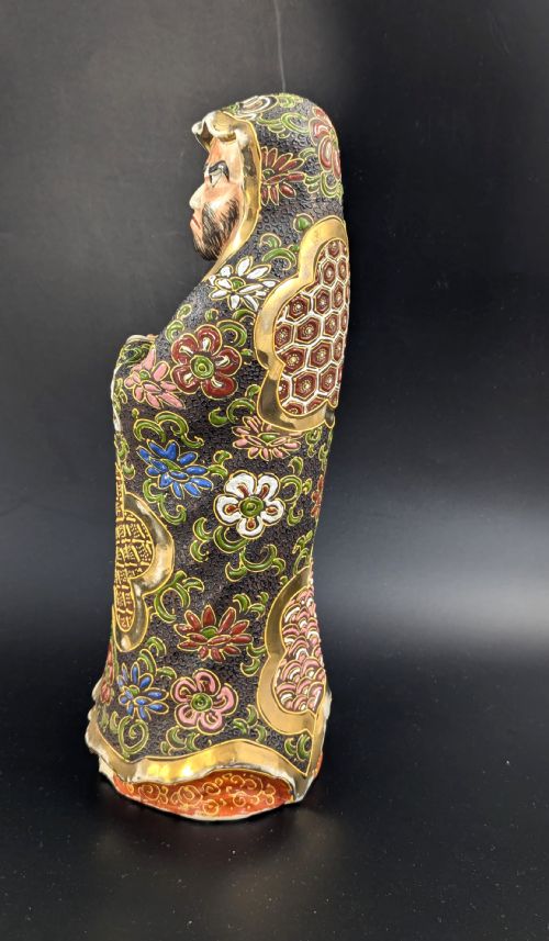 fig 2. A Japanese Satsuma earthenware figurine depicting a bearded Daruma monk wearing a hooded robe with polychrome enamels and gold accents.