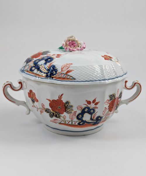 fig 3. An antique white porcelain lidded broth cup decorated with hand-painted red and blue floral motifs, featuring twin scroll handles and a sculpted floral lid finial.