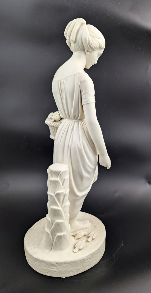 fig 3. An off-white Parian porcelain figurine depicting a standing classical female figure holding a fruit basket on a circular base.