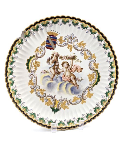 fig 1. A pair of 18th-century French tin-glazed earthenware display plates with hand-painted putti motifs, armorial shields, and green scalloped borders.