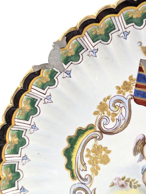 fig 2. A pair of 18th-century French tin-glazed earthenware display plates with hand-painted putti motifs, armorial shields, and green scalloped borders.