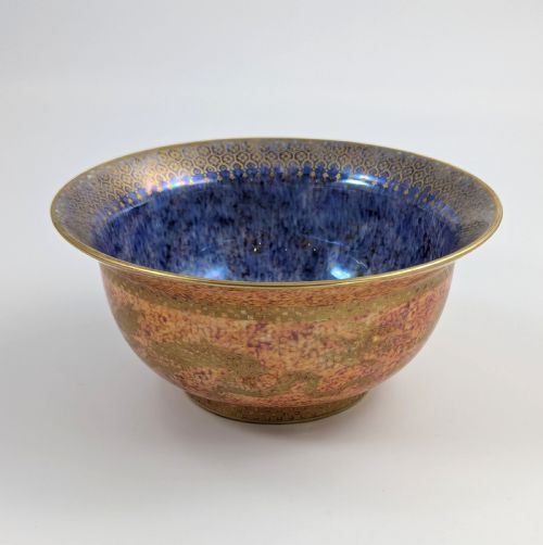 fig 1. A circular ceramic bowl displaying a mottled orange and gold exterior with a deep speckled blue interior bordered by detailed gilt geometric patterns.