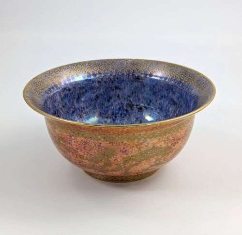 fig 2. A circular ceramic bowl displaying a mottled orange and gold exterior with a deep speckled blue interior bordered by detailed gilt geometric patterns.