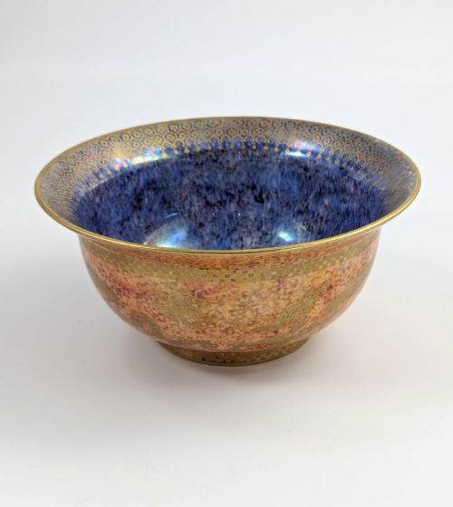 fig 3. A circular ceramic bowl displaying a mottled orange and gold exterior with a deep speckled blue interior bordered by detailed gilt geometric patterns.
