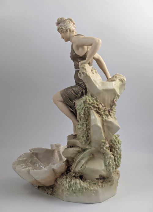 fig 2. An Art Nouveau Royal Dux porcelain centrepiece depicting a draped female bather standing atop rockwork above a large shell-shaped basin.