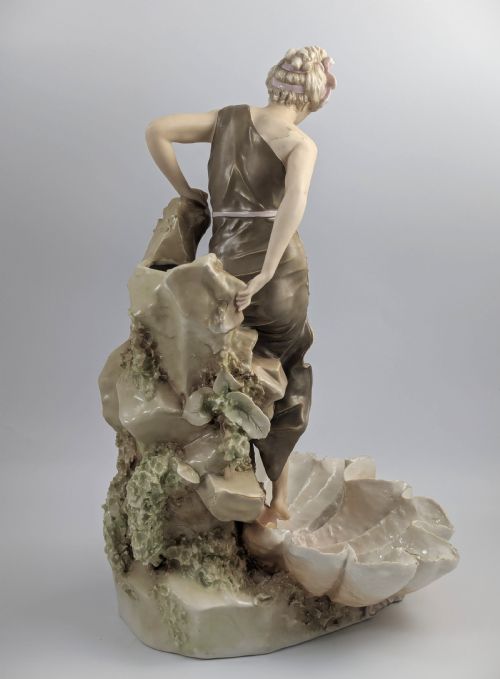 fig 4. An Art Nouveau Royal Dux porcelain centrepiece depicting a draped female bather standing atop rockwork above a large shell-shaped basin.