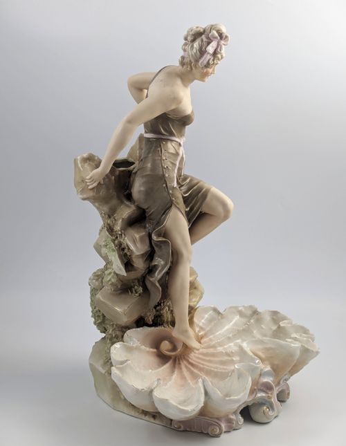 fig 5. An Art Nouveau Royal Dux porcelain centrepiece depicting a draped female bather standing atop rockwork above a large shell-shaped basin.