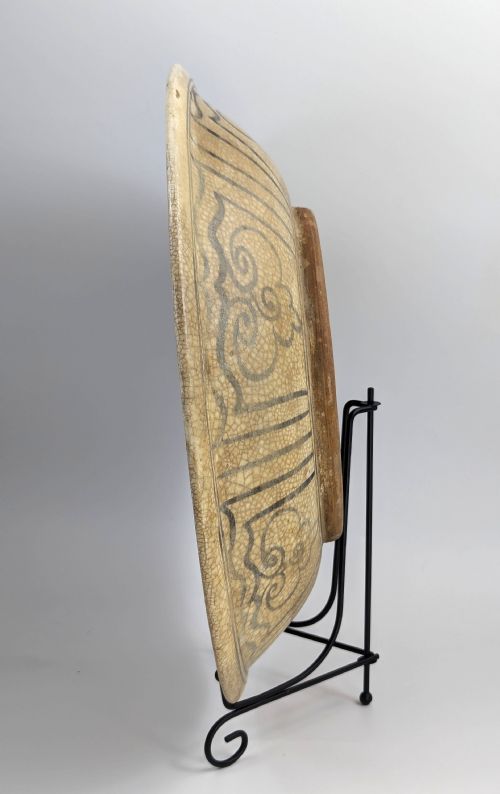 fig 2. A circular antique ceramic dish featuring a central underglaze grey fish design on a crazed cream ground.