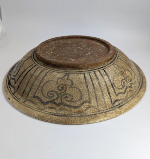 fig 4. A circular antique ceramic dish featuring a central underglaze grey fish design on a crazed cream ground.