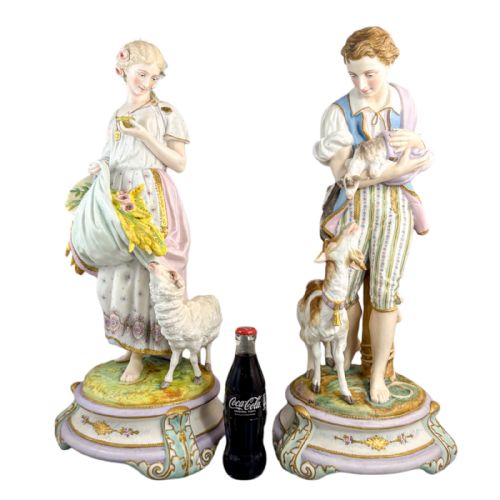 fig 1. A pair of large French bisque porcelain sculptures featuring a shepherd and shepherdess with animals on gilded bases.
