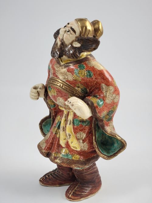 fig 1. A Japanese Kutani porcelain figurine depicting a bearded male figure in a red and gold patterned robe with raised moriage enamel detailing.