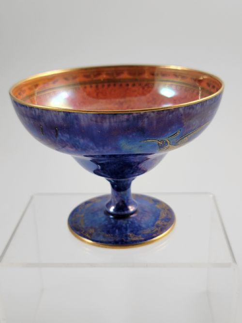 fig 1. A footed porcelain melba cup featuring a mottled cobalt blue exterior with gilt hummingbird motifs and a bright orange iridescent interior finish.