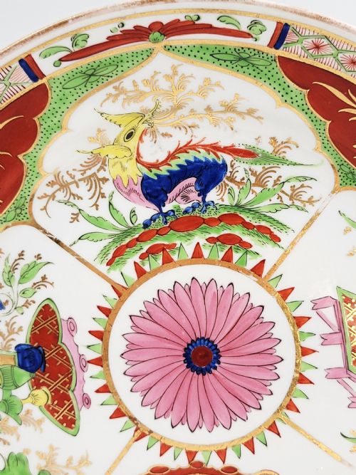 fig 2. A circular antique English porcelain dessert plate decorated with hand-painted Chinoiserie panels, mythical dragons, and a pink central flower motif.