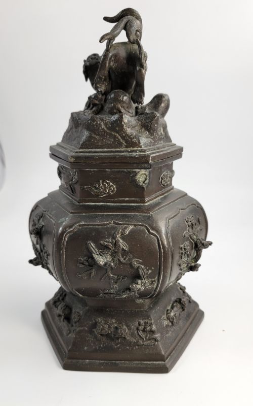 fig 2. A dark patinated hexagonal bronze incense burner featuring floral relief panels and topped with a sculpted Fu lion finial.