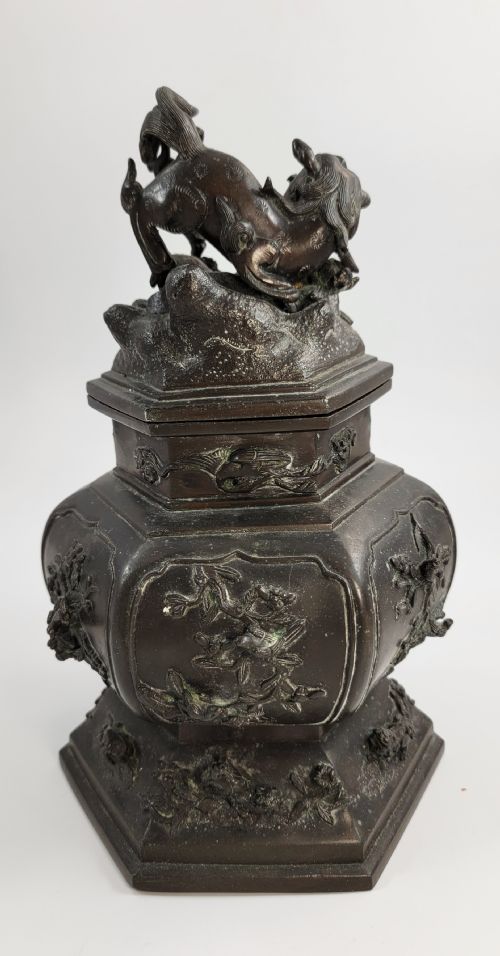 fig 3. A dark patinated hexagonal bronze incense burner featuring floral relief panels and topped with a sculpted Fu lion finial.