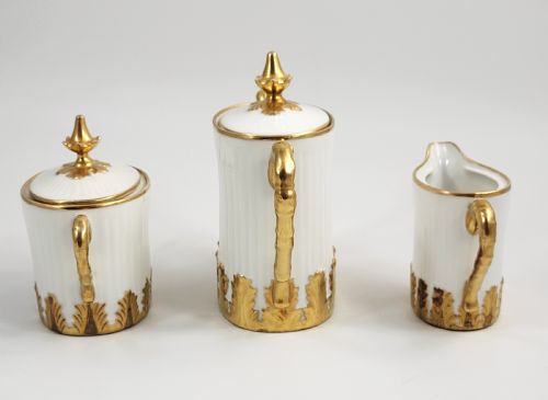 fig 1. A three-piece white porcelain coffee set featuring a pot, sugar bowl, and cream jug with fluted bodies and gilded acanthus leaf detailing.