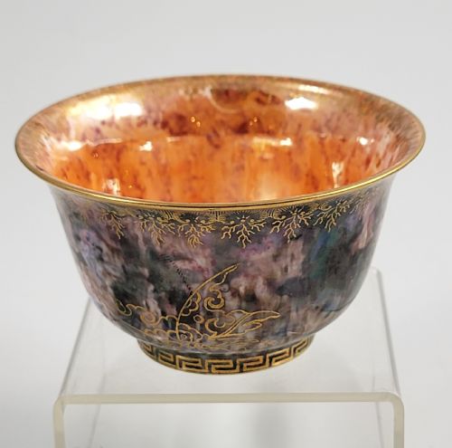fig 1. A circular porcelain bowl featuring a mottled iridescent purple exterior decorated with gilt butterfly motifs and a gold-toned orange interior.