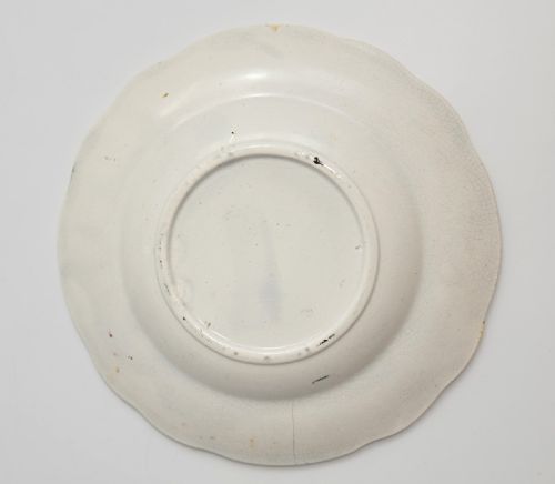 fig 2. A circular Victorian ceramic plate featuring a central black transfer print of the Battle of Tchernaya surrounded by a scalloped rim with green, red, and yellow enamel accents.