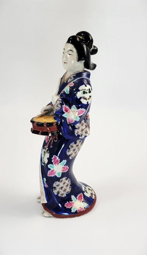 fig 1. Japanese Kutani porcelain figurine of a standing lady in a cobalt blue floral kimono playing a hand drum.