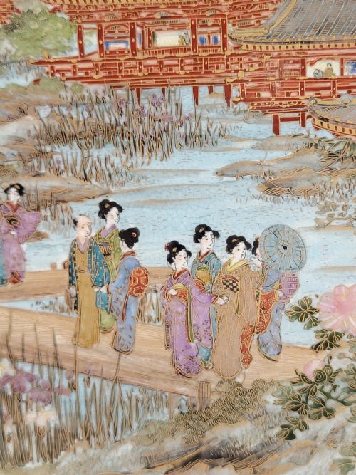 fig 2. A circular Meiji period Satsuma earthenware plate featuring finely detailed figures, temples, and wisteria framed by a gilt geometric border.