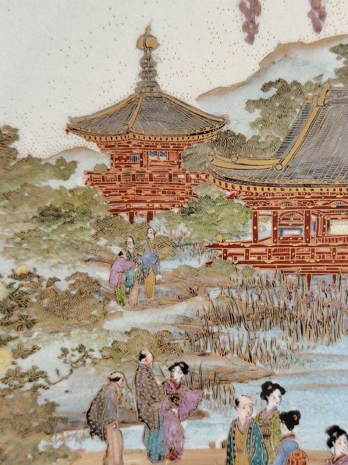 fig 4. A circular Meiji period Satsuma earthenware plate featuring finely detailed figures, temples, and wisteria framed by a gilt geometric border.