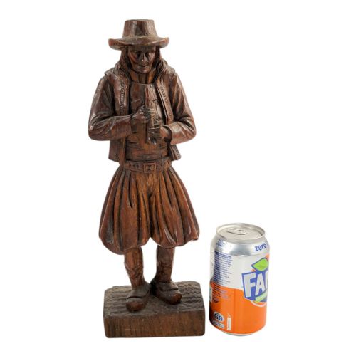 fig 1. A nineteenth-century hand-carved oak figure depicting the Pied Piper standing on a rectangular base while playing a musical pipe.