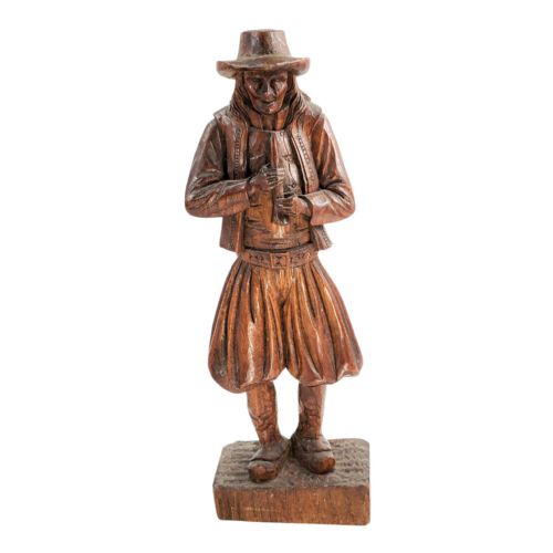fig 2. A nineteenth-century hand-carved oak figure depicting the Pied Piper standing on a rectangular base while playing a musical pipe.