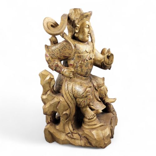 fig 1. A 19th-century carved wooden Chinese temple guardian figure with intricate gilded and polychrome surface detail seated on a carved rocky base.
