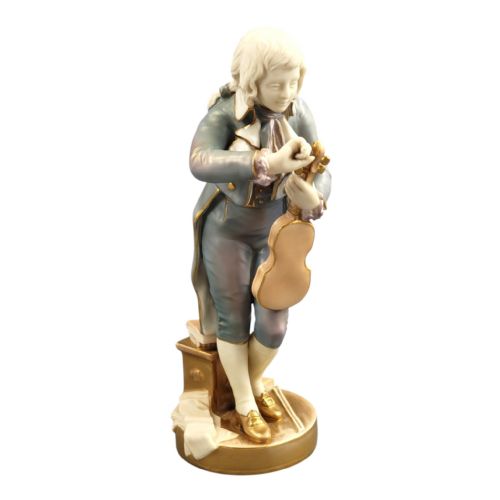 fig 1. A Royal Worcester porcelain figurine depicting a young Mozart in 18th-century attire tuning a violin atop a gilded circular base.