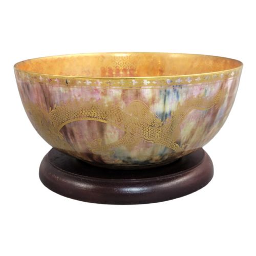 fig 1. A circular ceramic bowl featuring a mottled pink and purple iridescent lustre glaze adorned with detailed gilded dragon motifs.