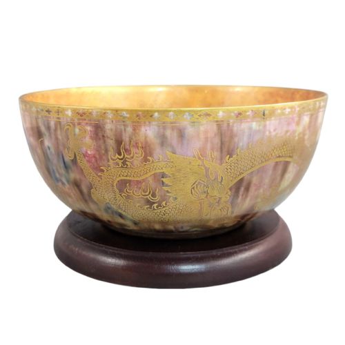 fig 2. A circular ceramic bowl featuring a mottled pink and purple iridescent lustre glaze adorned with detailed gilded dragon motifs.
