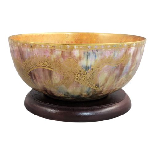 fig 3. A circular ceramic bowl featuring a mottled pink and purple iridescent lustre glaze adorned with detailed gilded dragon motifs.