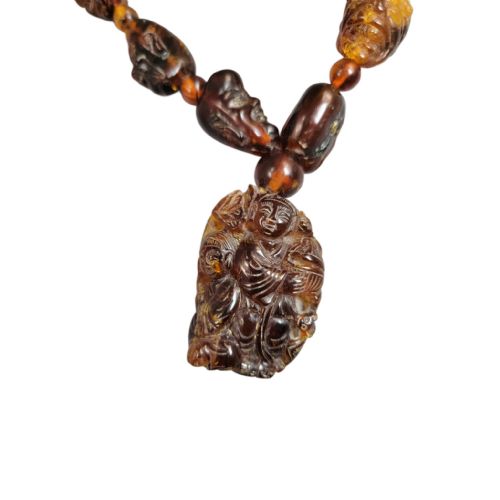 fig 1. A Chinese amber necklace featuring eighteen hand-carved luohan head beads and a figural carved pendant drop.