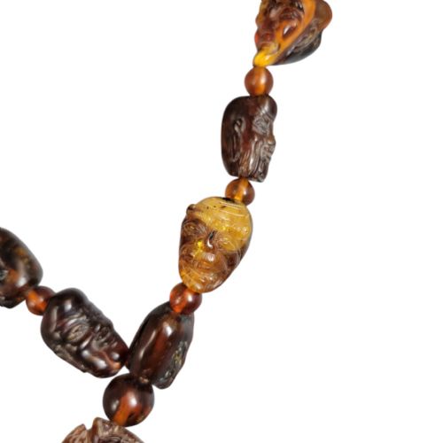 fig 2. A Chinese amber necklace featuring eighteen hand-carved luohan head beads and a figural carved pendant drop.