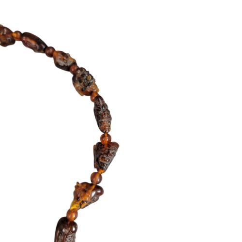 fig 3. A Chinese amber necklace featuring eighteen hand-carved luohan head beads and a figural carved pendant drop.