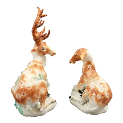 fig 1. A pair of 18th-century Derby porcelain figures depicting a reclining stag with branched antlers and a doe, painted with chestnut-spotted coats on floral-adorned white bases.