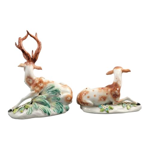fig 2. A pair of 18th-century Derby porcelain figures depicting a reclining stag with branched antlers and a doe, painted with chestnut-spotted coats on floral-adorned white bases.