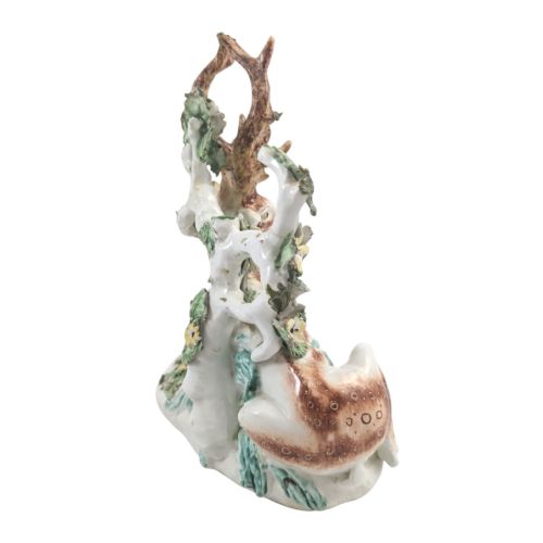 fig 3. An 18th-century soft-paste porcelain figurine depicting a recumbent brown and white spotted stag resting in front of a leafy bocage with small yellow flowers.