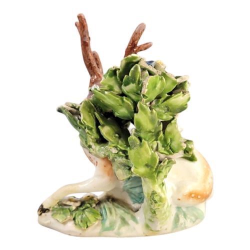 fig 2. An 18th-century Derby porcelain figure depicting a spotted recumbent stag sitting before a leafy floral bocage backdrop.