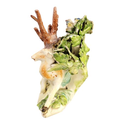 fig 3. An 18th-century Derby porcelain figure depicting a spotted recumbent stag sitting before a leafy floral bocage backdrop.