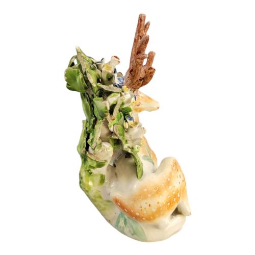 fig 4. An 18th-century Derby porcelain figure depicting a spotted recumbent stag sitting before a leafy floral bocage backdrop.